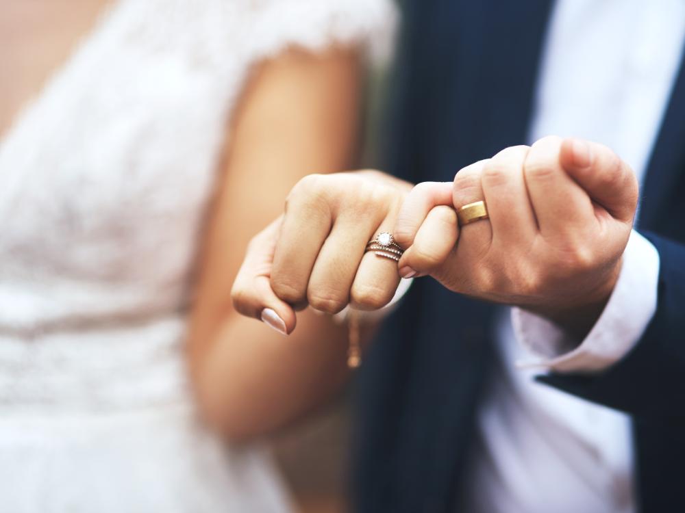 Brudpars händer som visar bröllopsringarna